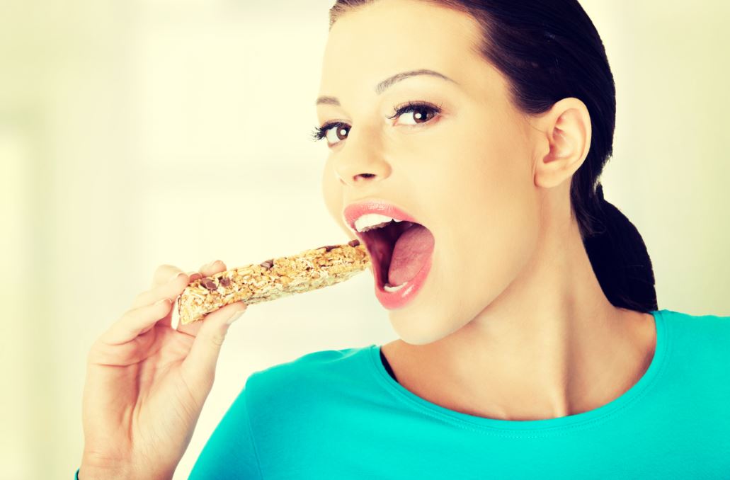 Chica comiendo barrita energética.