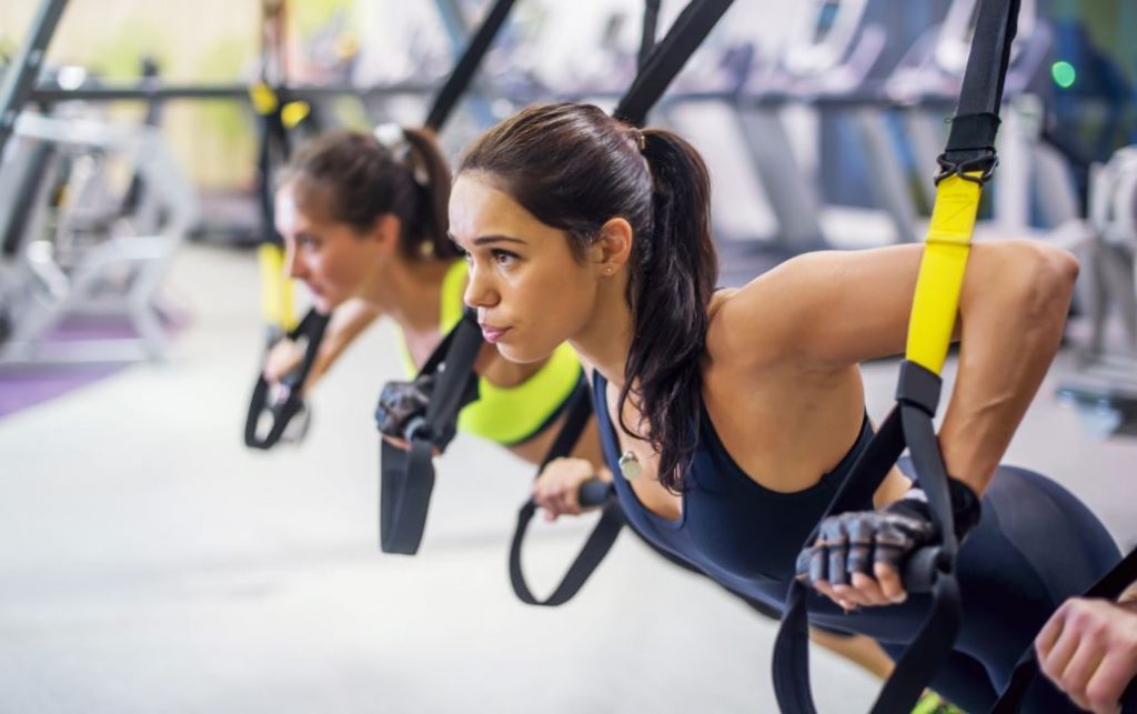 Chica concentrada en un entrenamiento tipo TRX.