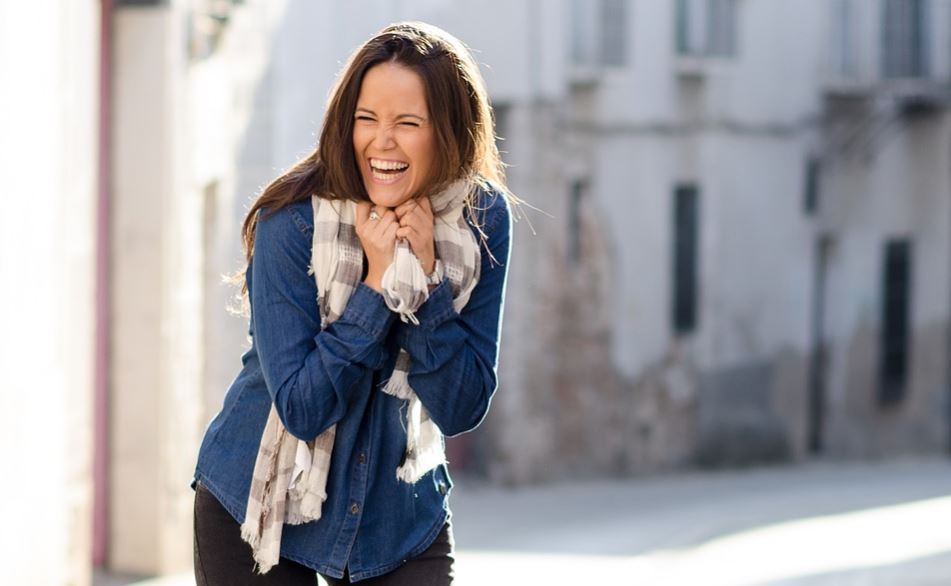 Chica feliz riendo en la calle.