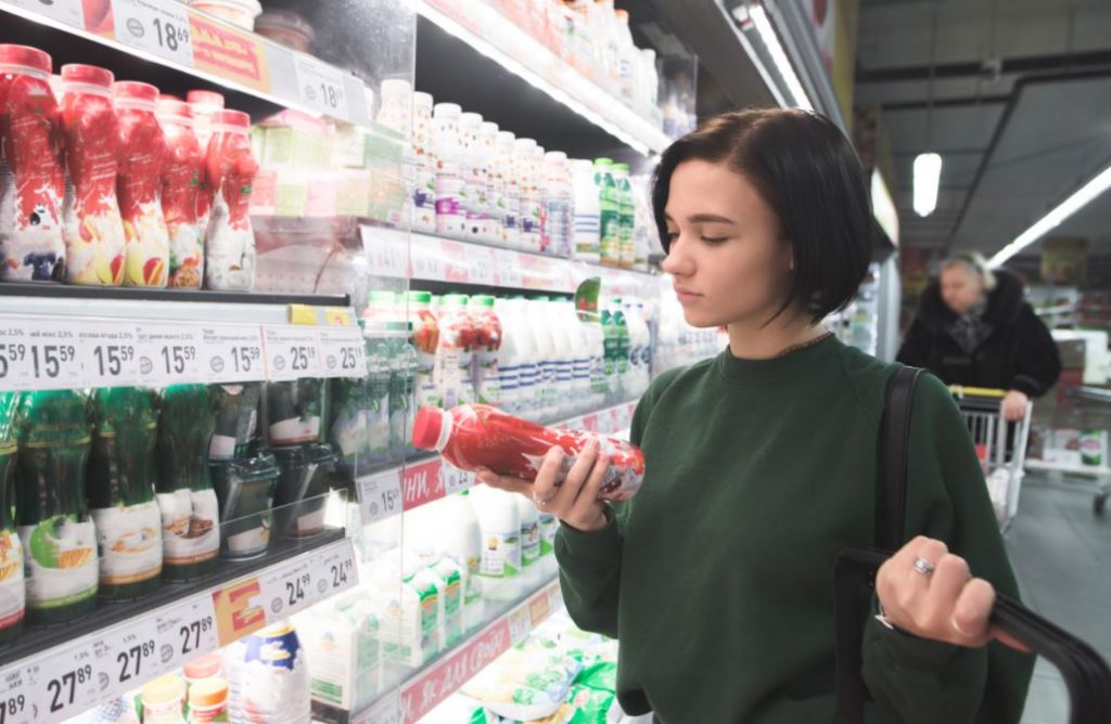 Una chica está mirando la etiqueta de un producto en el supermercado.