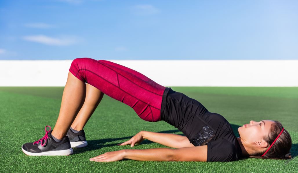 Chica haciendo puente de caderas, trabajando core y abdominales.
