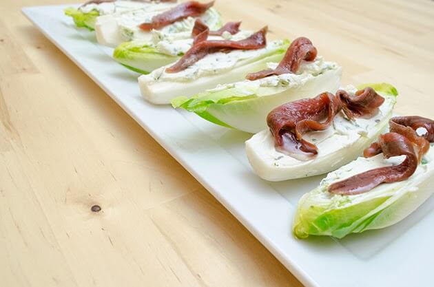 El primer paso para preparar estas endivias con queso y anchoas, es lavar bien la endivia y partirlas por la mitad a lo largo.