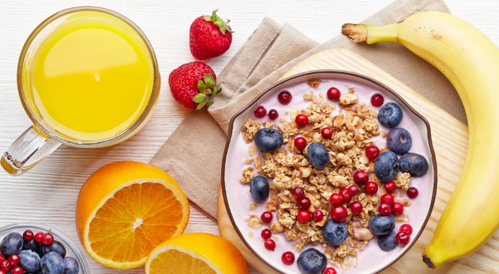 Desayuno equilibrado de yogur, zumo natural y plátano.