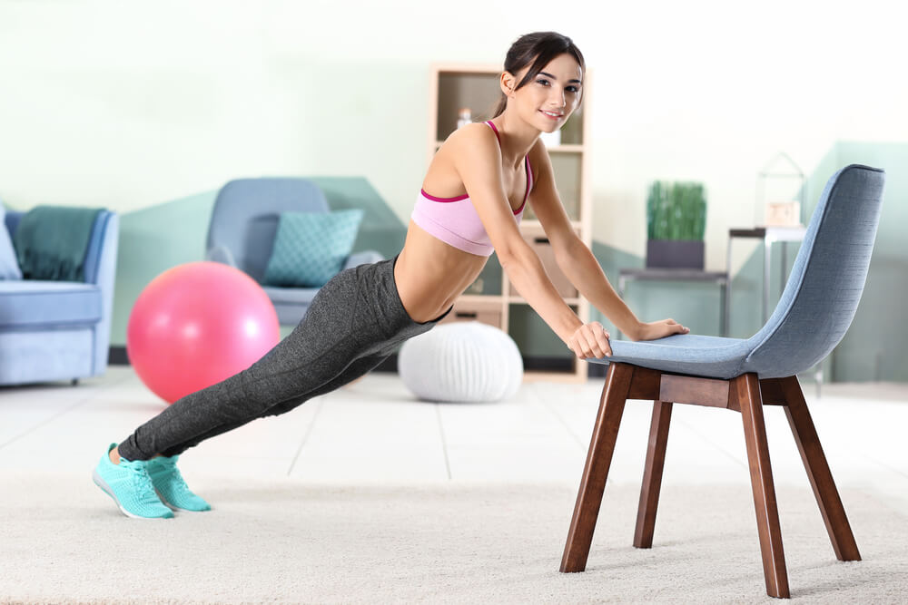 mujer realizando lagartijas estilo diagonal con una silla