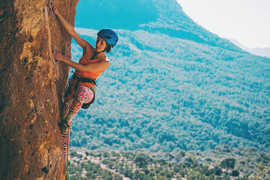 Chica realizando escalada en montaña a grandes alturas.