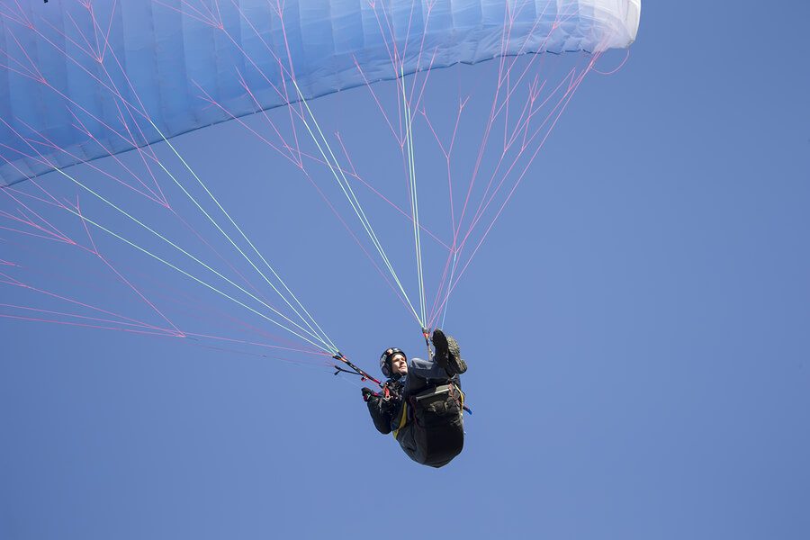 Hombre descendiendo en parapente, uno de los deportes de riesgo más practicados.