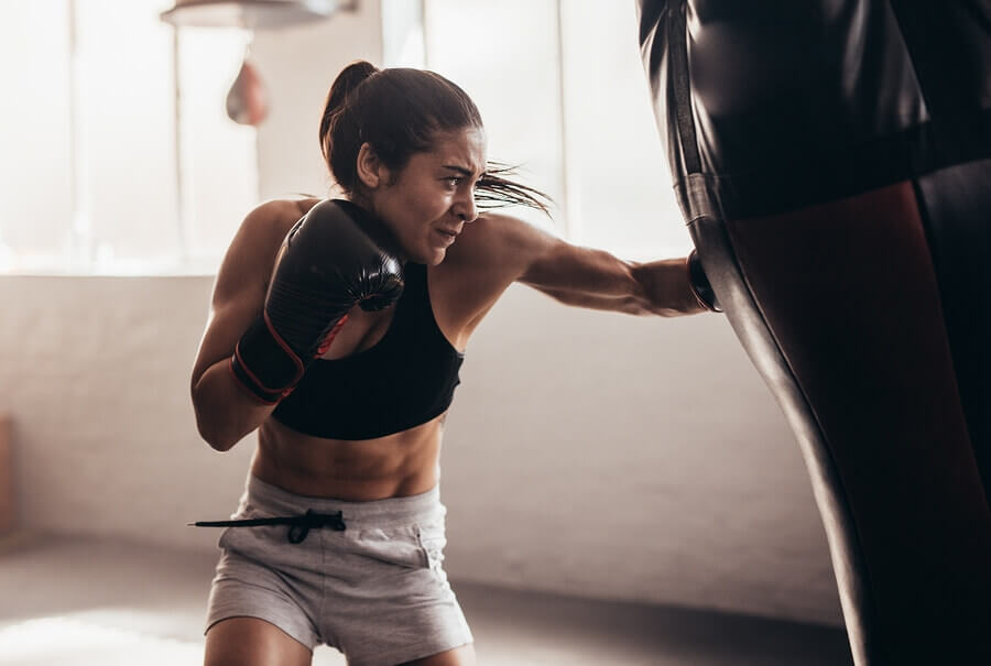 Mujer practicando con una bolsa de boxeo.