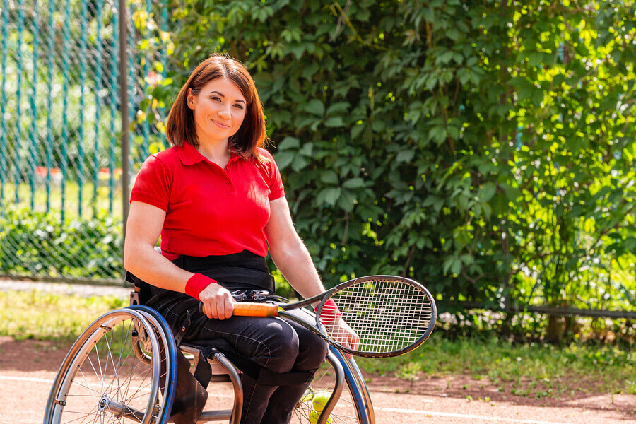 Mujer con discapacidad física sobre silla de ruedas para jugar al tenis adaptado.