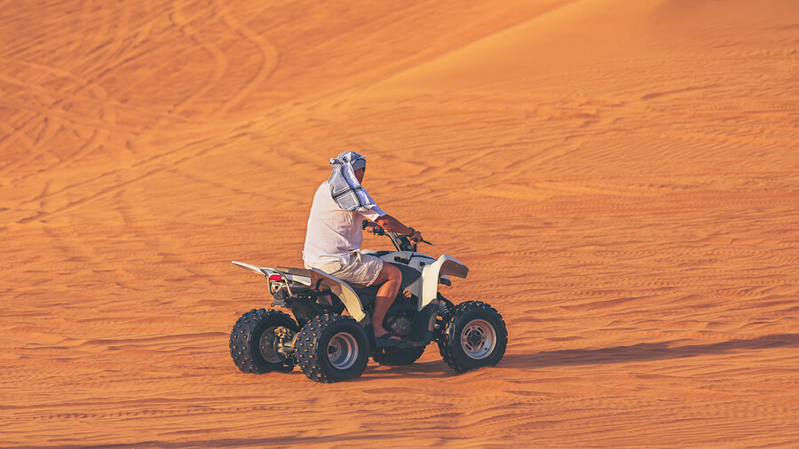 Hombre andando en cuatriciclo por el desierto.