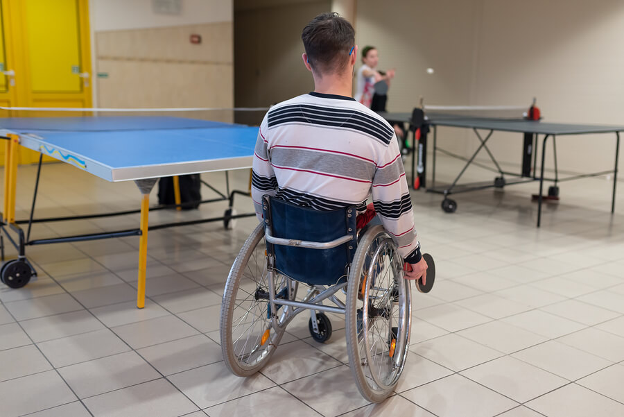 Joven jugando al tenis de mesa en silla de ruedas.