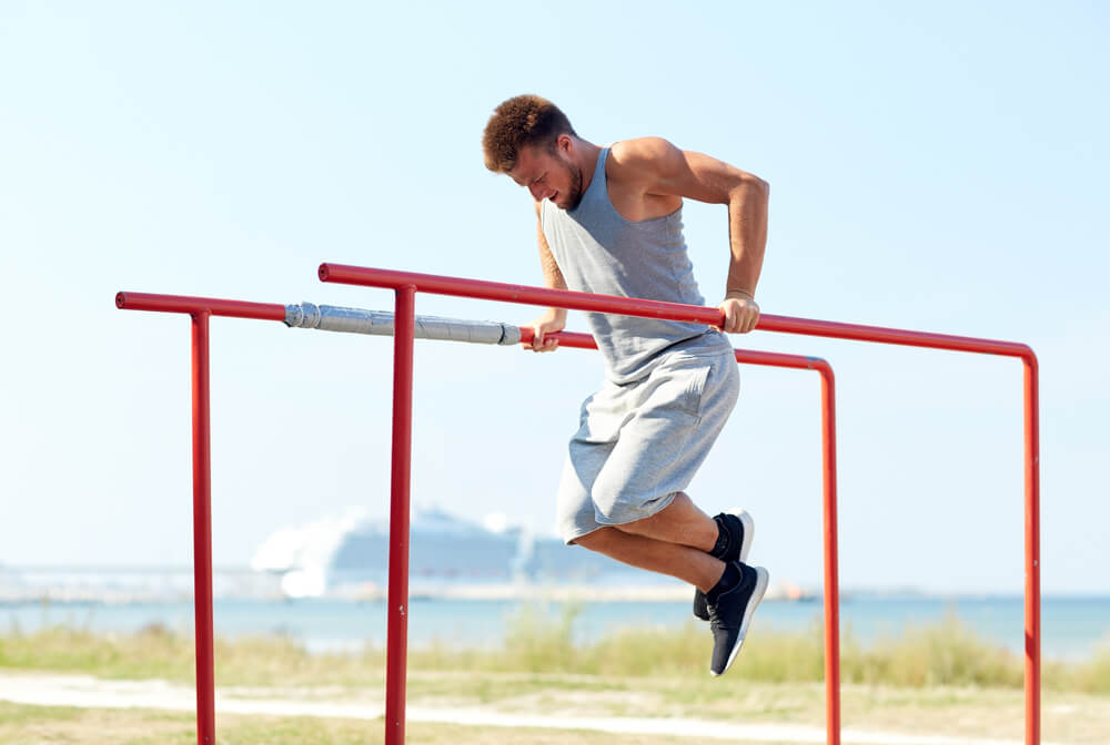 Joven haciendo entrenamiento de tríceps en barras paralelas.