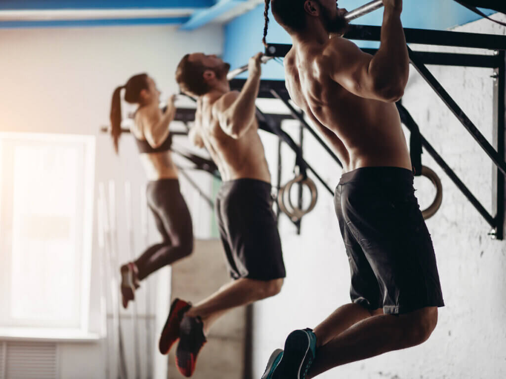 Grupo de entrenamiento de crossfit realizando dominadas.