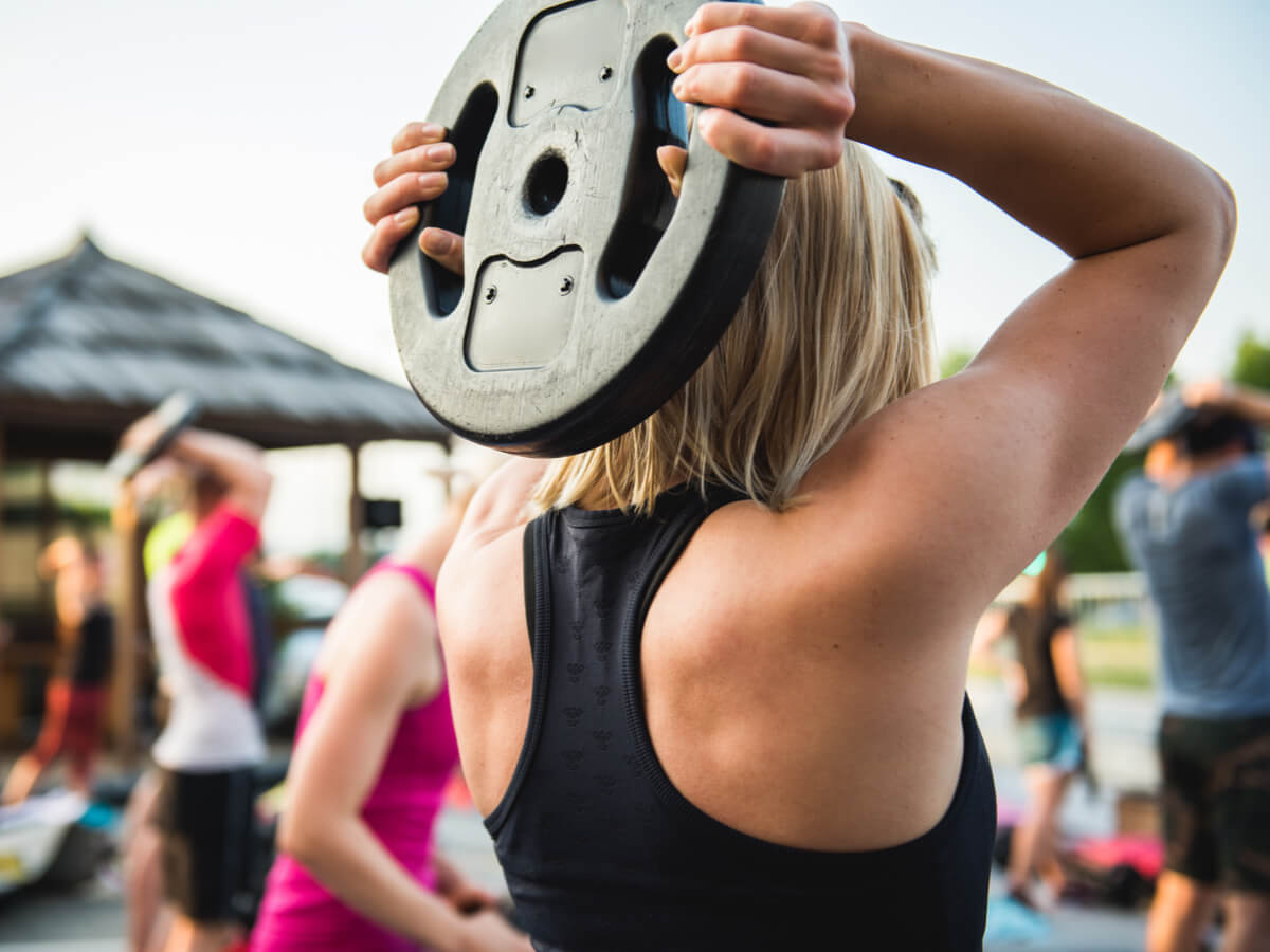 Mujer haciendo ejercicio con disco durante clase de bodypump.