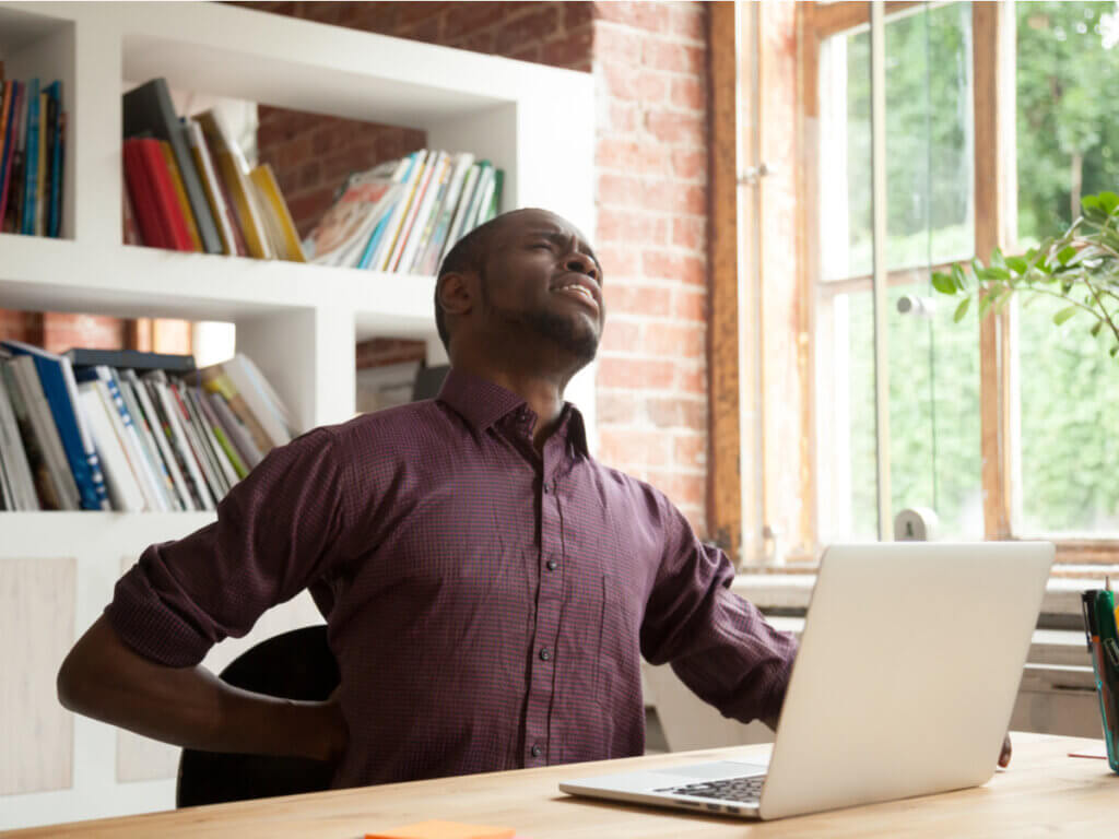 Hombre trabaja en casa y se queja de un dolor en la espalda.