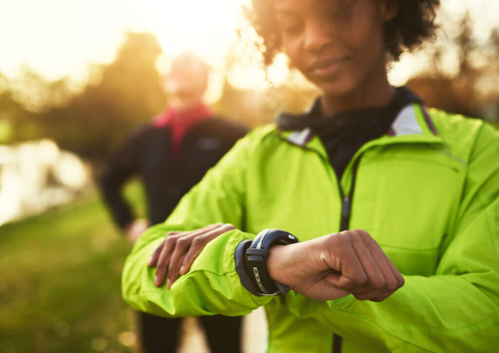 Mujer mirando una pulsera fitness al entrenar.