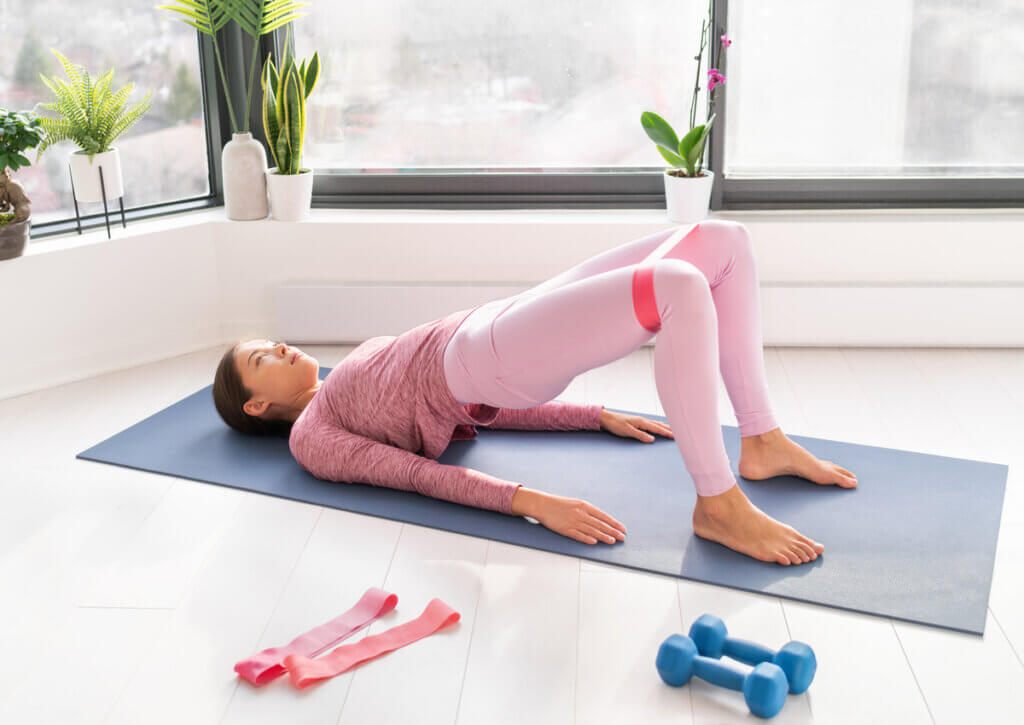 Mujer haciendo pilates con bandas elásticas.