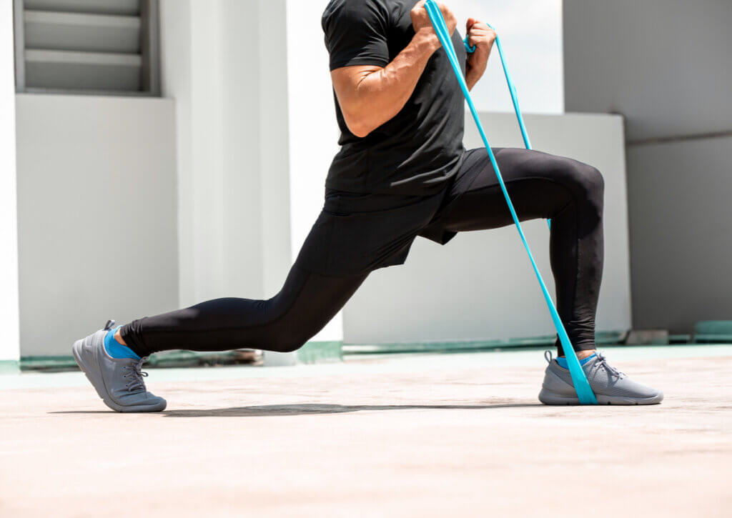 Joven haciendo zancada con banda elástica.