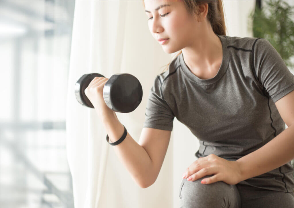 Mujer realizando curl de bíceps como entrenamiento de fuerza.