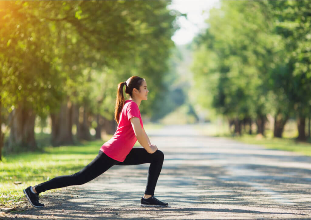 Mujer joven realizando estiramiento de cadera en el parque.