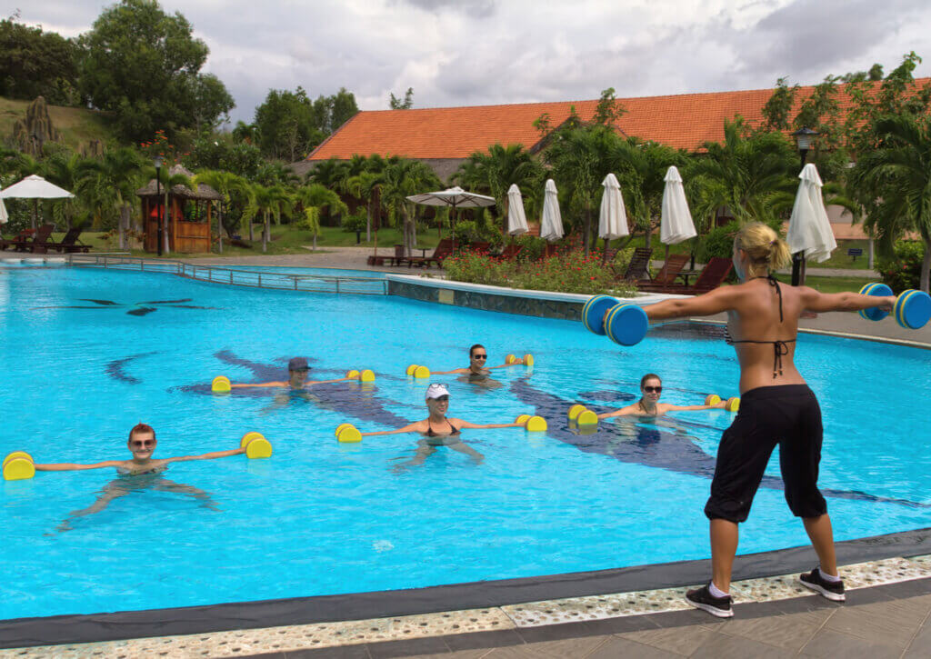Grupo de personas realizando gimnasia acuática con mancuernas.