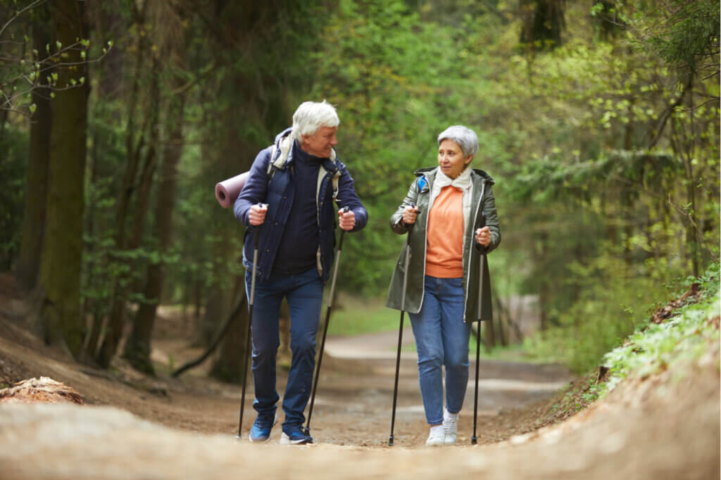 Personas mayores realizando caminata nórdica por el bosque.