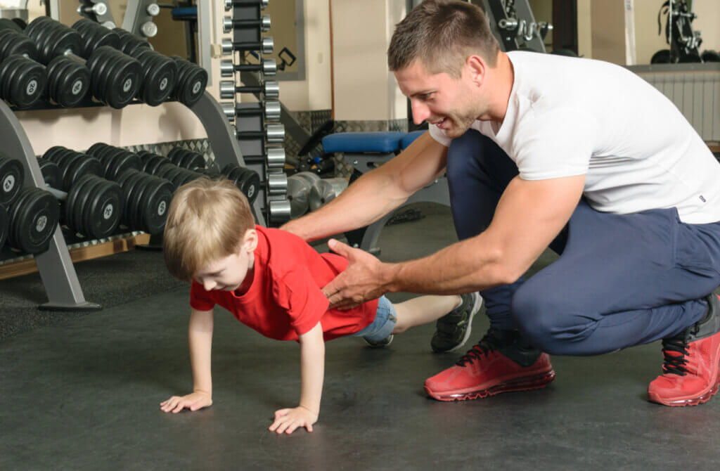 Niño aprende a hacer la plancha con su padre.