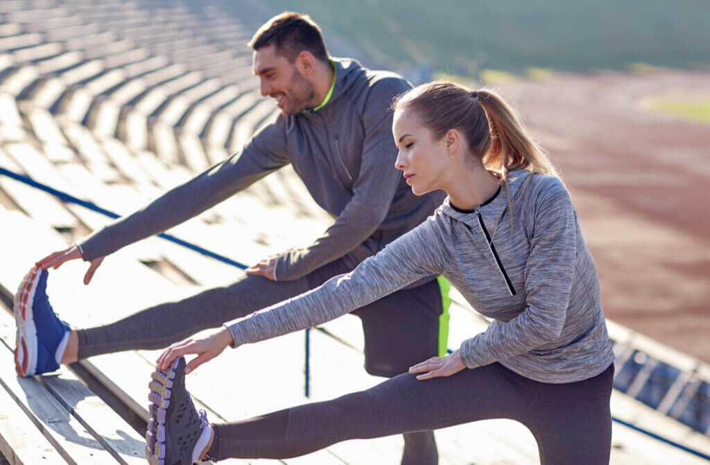 Pareja entrena al aire libre y estira los isquiotibiales.
