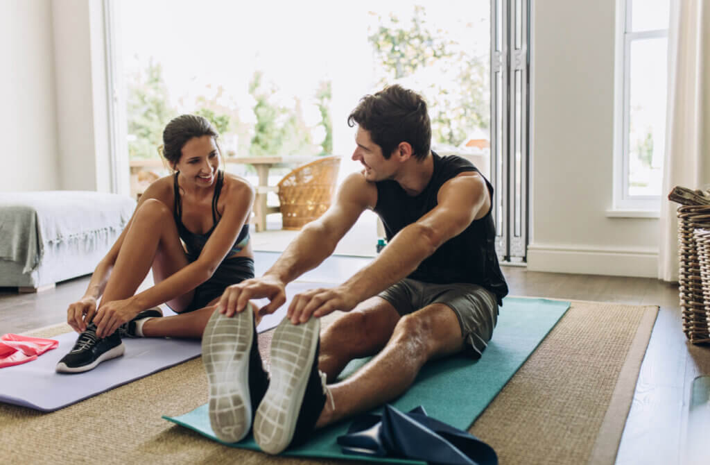 Pareja realizando en casa un ejercicio para estirar los isquiotibiales.