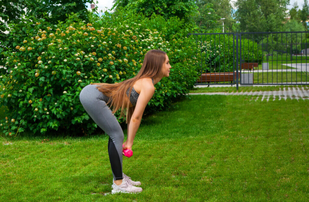 Mujer hace peso muerto para entrenar las lumbares en casa.