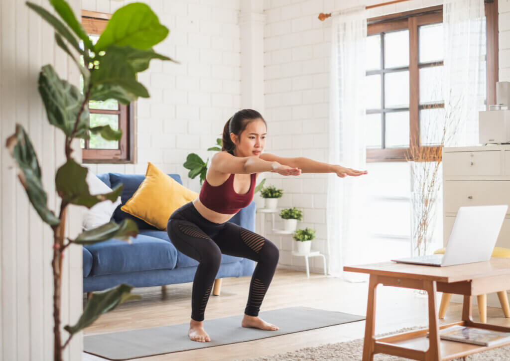 Mujer realizando una rutina de cardio yoga desde casa.