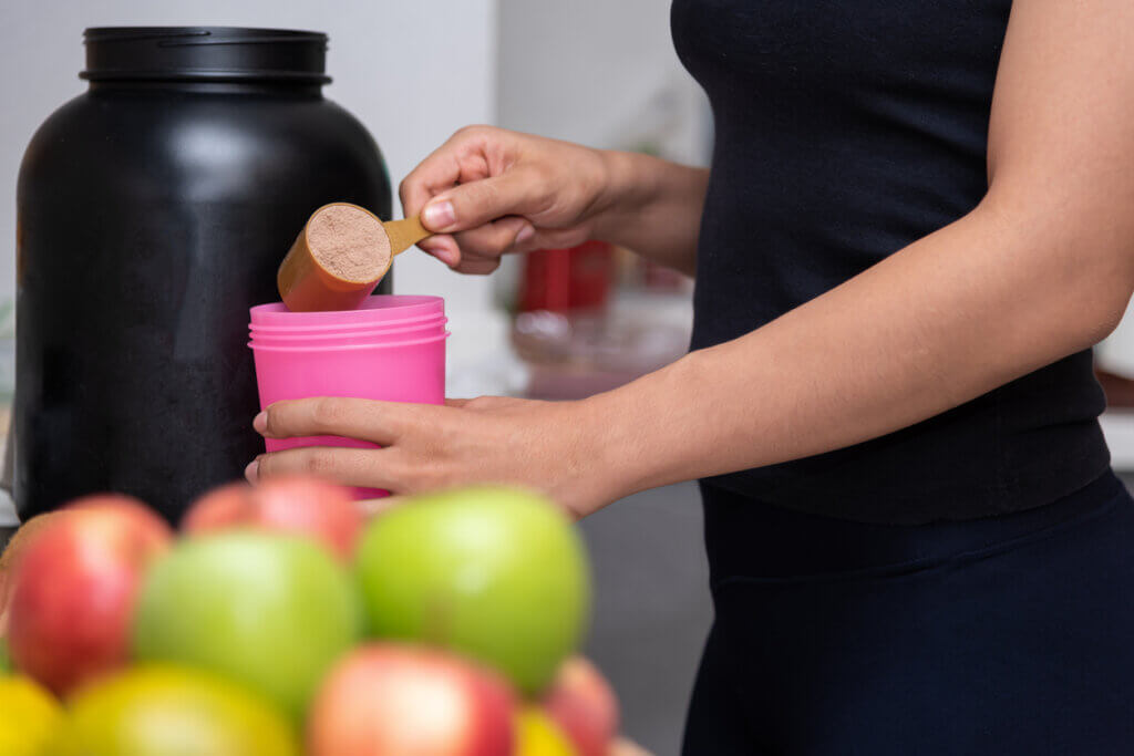 Mujer preparando un batido de proteínas en su casa.
