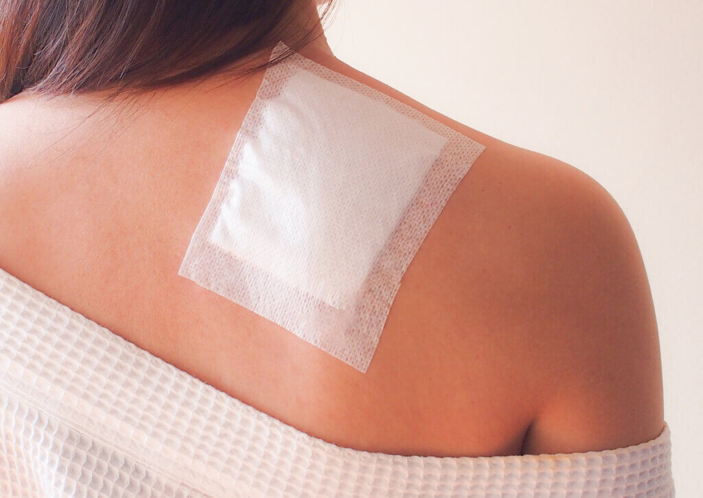 Mujer con un parche para el dolor colocado sobre el hombro.