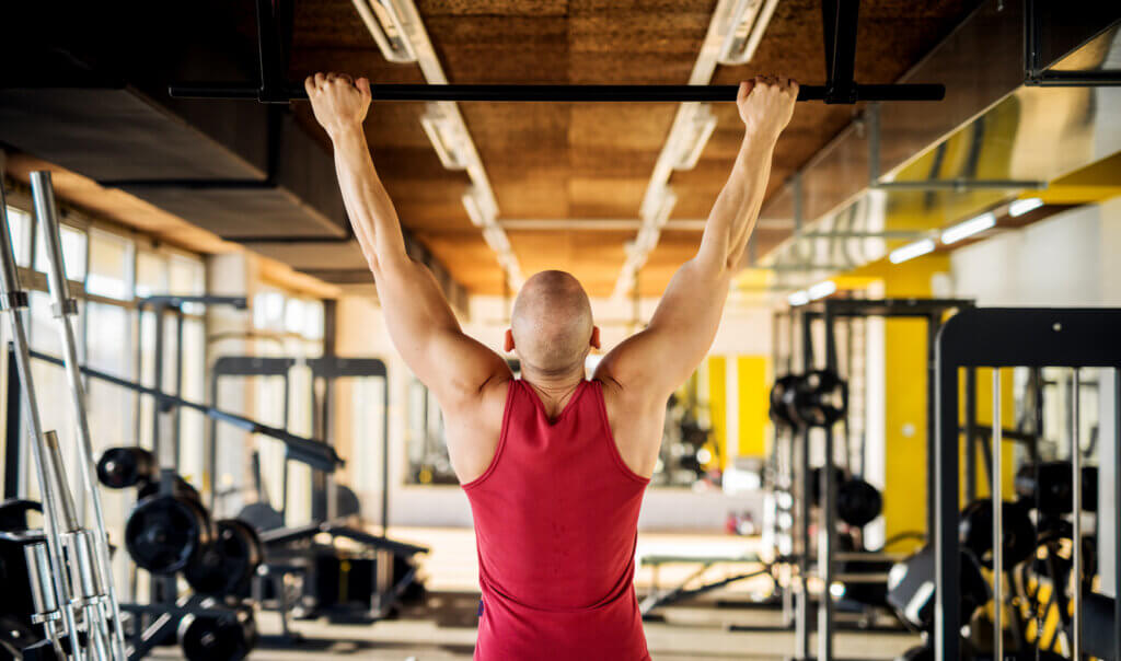 Hombre realizando la prueba de dominadas en un gimnasio.