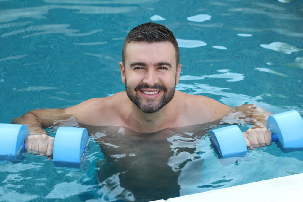 Hombre haciendo propiocepción en el agua con pesas.