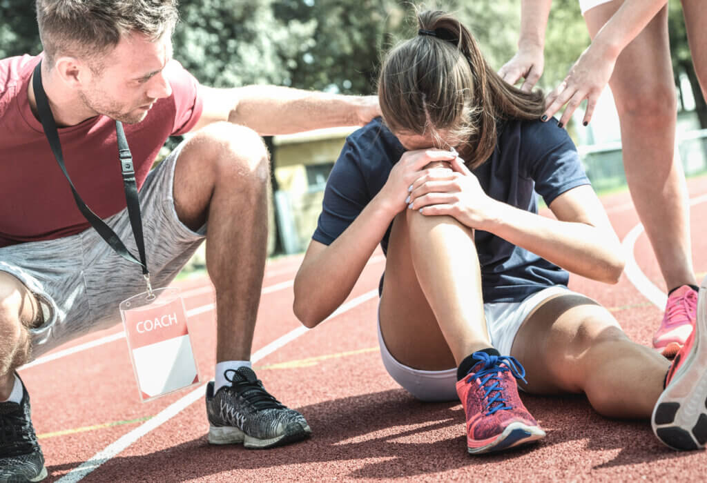 Mujer sujetando su rodilla tras sufrir un esguince de ligamentos.