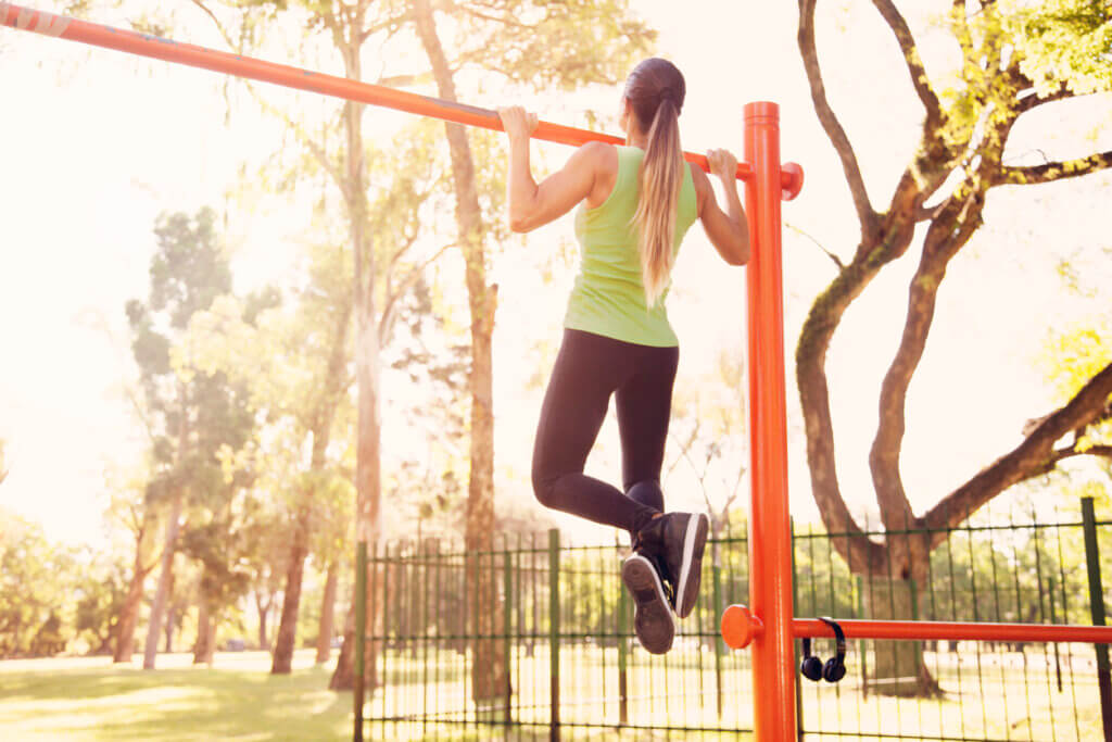Mujer realiza la prueba de dominadas al aire libre.