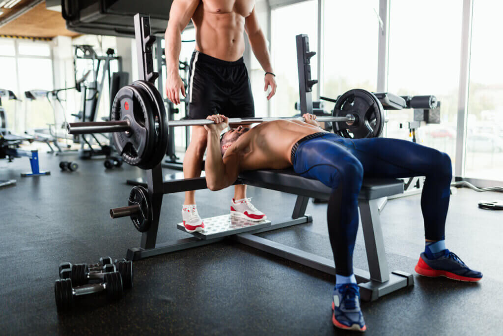 Hombre haciendo press de pecho con barra.