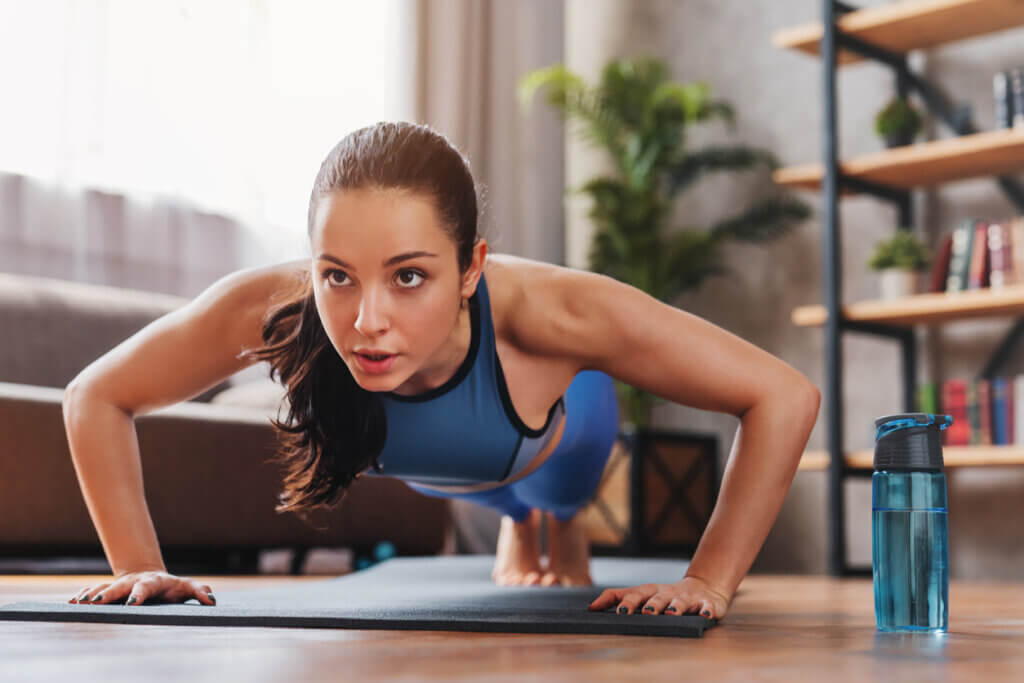 Mujer haciendo flexiones para construir músculo en casa.