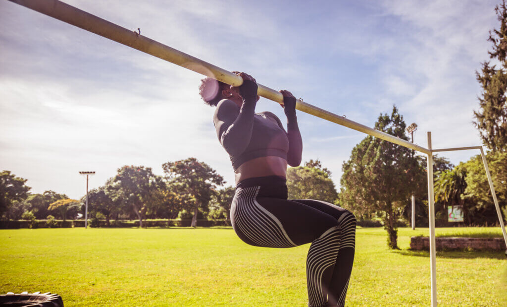 Mujer entrenando las dominadas supinas al aire libre.