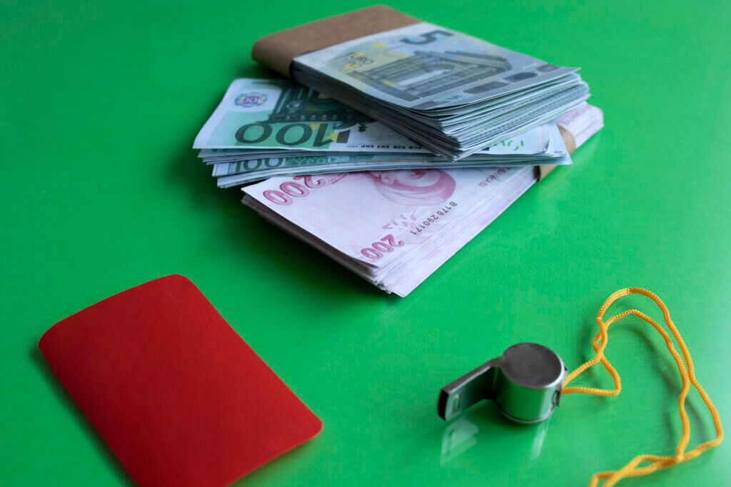 Dinero, tarjeta roja y silbato que representan el amaño de partidos