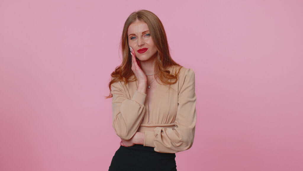 Mujer de pelo colorado sujetando su mandíbula