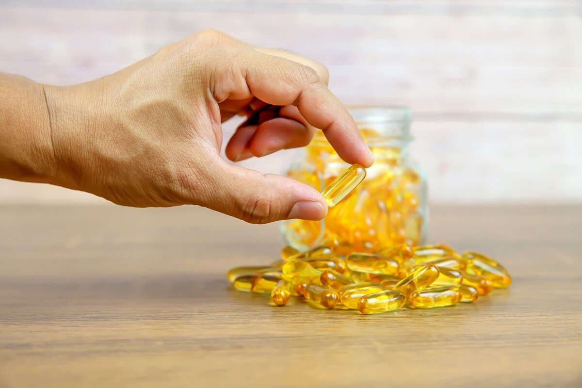 Mano sosteniendo una píldora de omega 3.