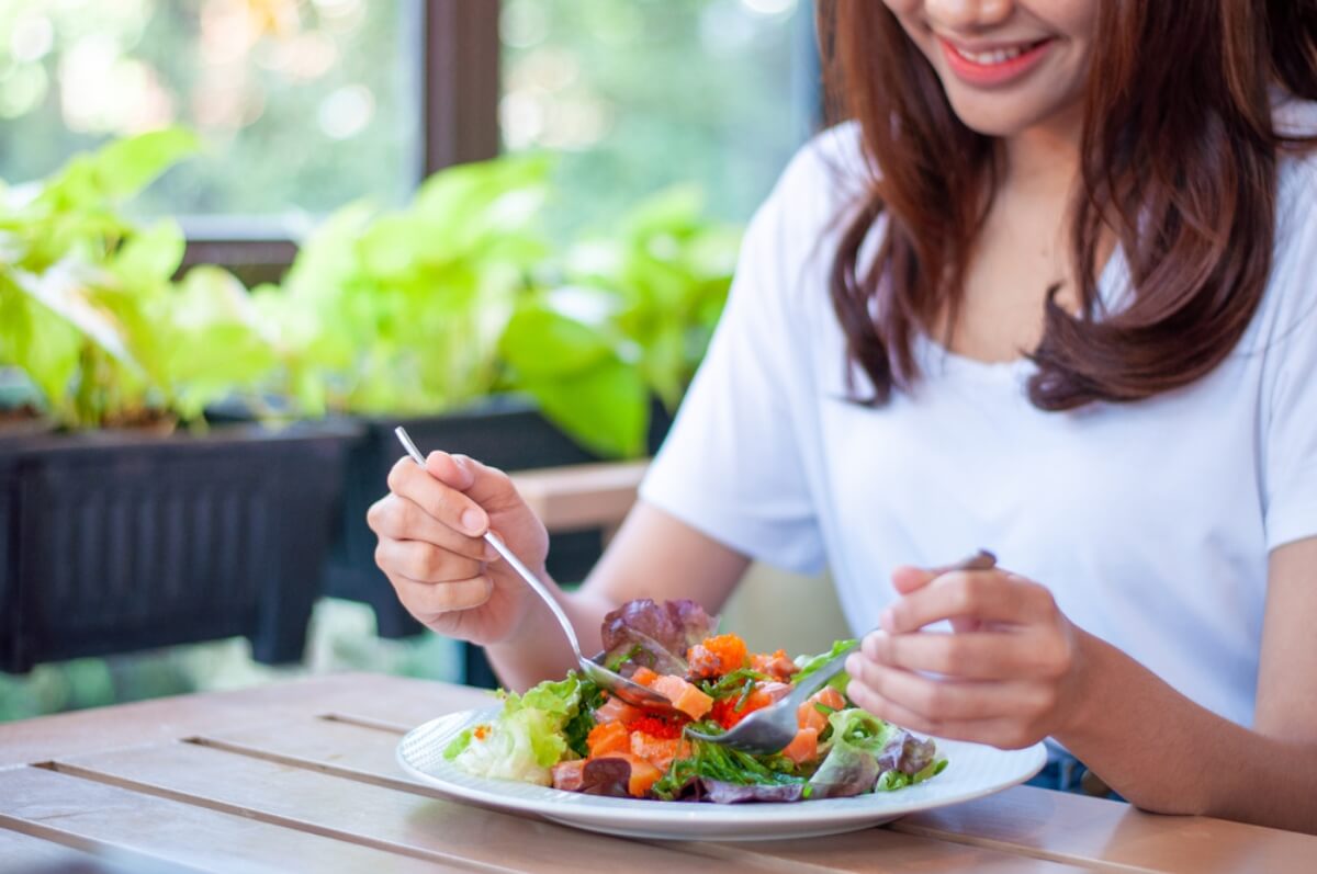Mujer comiendo verduras, alimento para el rendimiento deportivo.