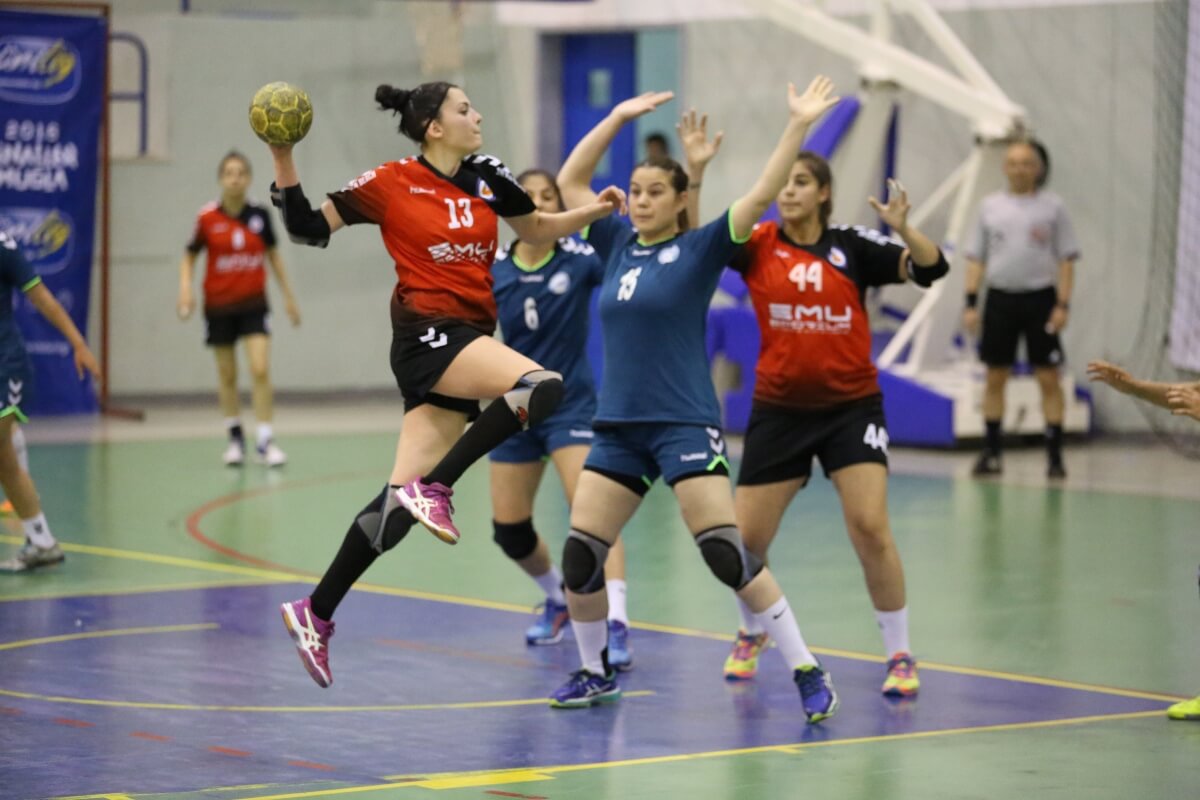 Mujeres practicando balonmano en coliseo.