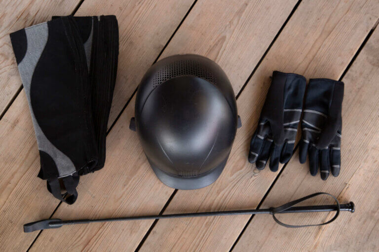 fusta, guantes, casco y protectores que hacen parte de la ropa de equitación